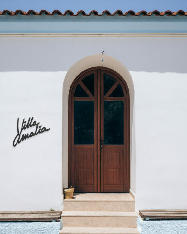 maison en crépis blanc avec sur sa façade un nom de maison en inox nommé "Maison Amalia"